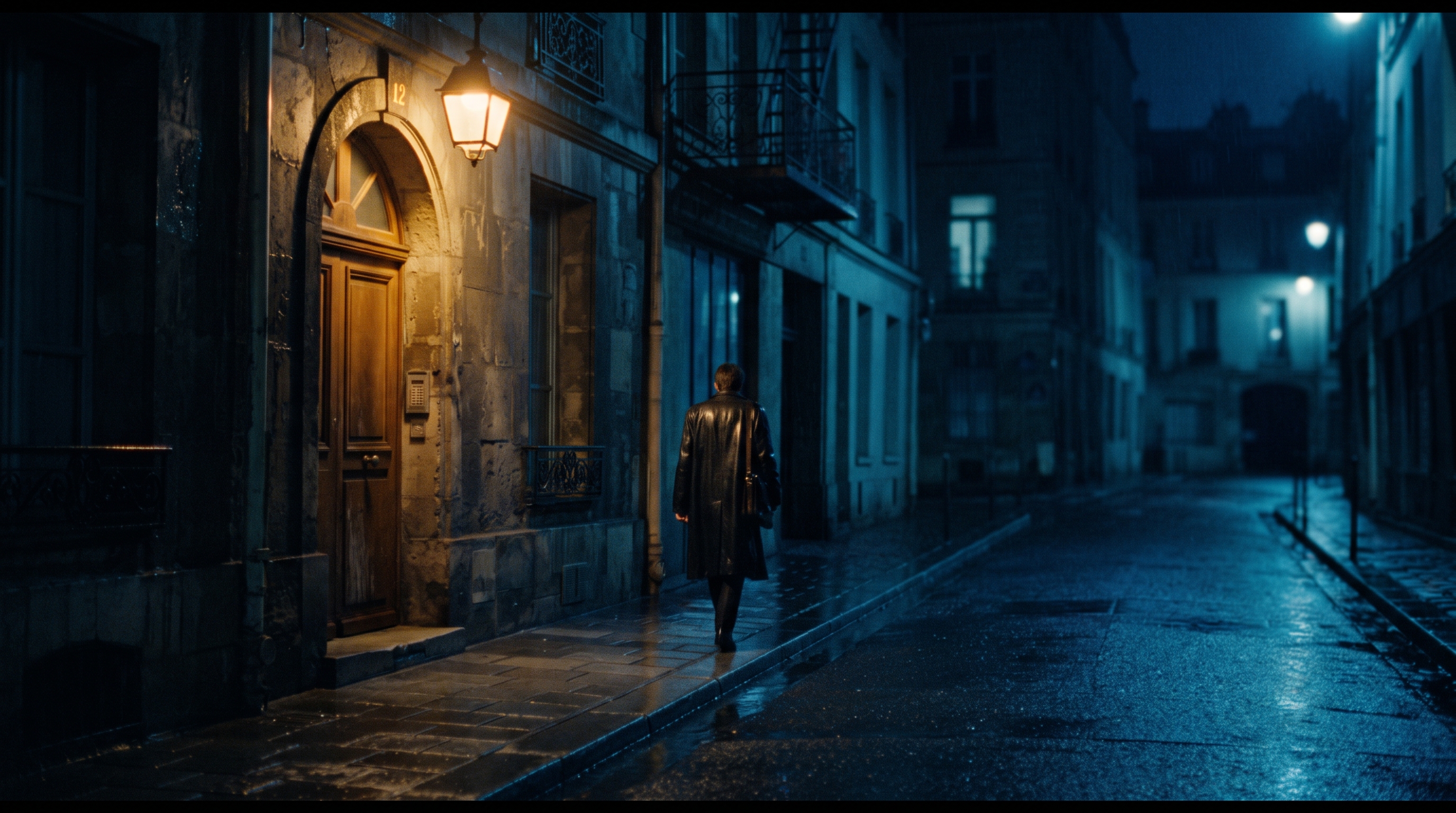 A rain-wet side street at night with one warm doorway lamp